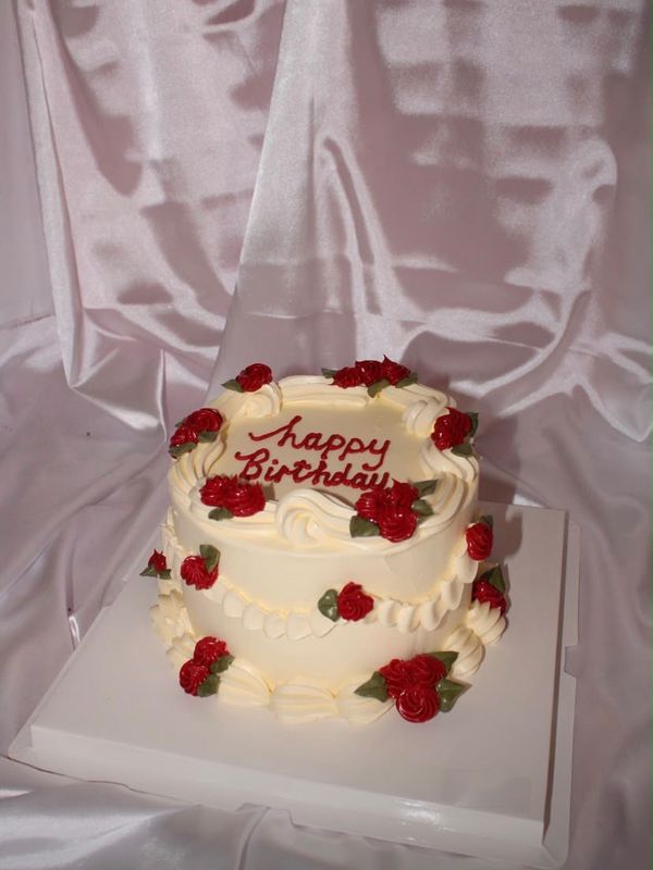 A cream cake with red roses and Happy Birthday